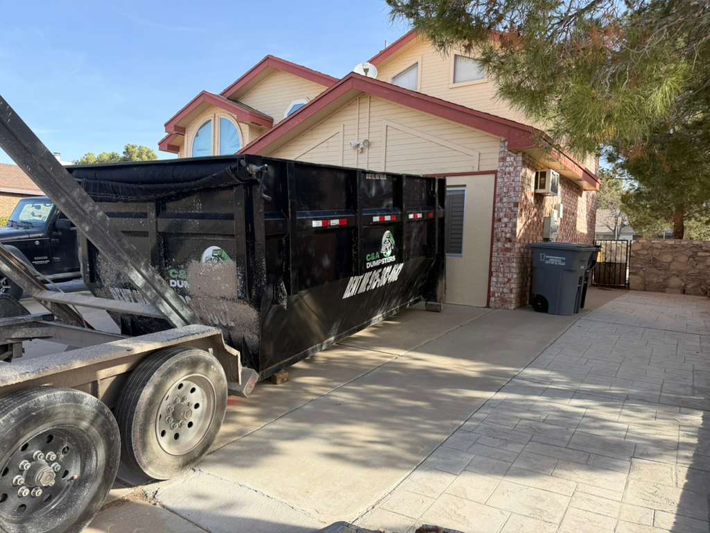 C&A Dumpster placed carefully near a residential garage